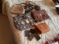Overview of all items arranged on bed showing variety of handbags, clutches, and wallets