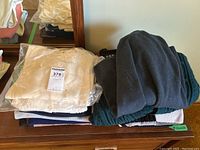 Top view of folded assorted sweaters and sweater vests including beige wool item sealed in plastic.