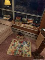 Overview of piles of hardcover books on window seat and poster sheet on floor