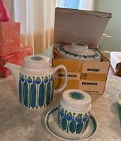 Teapot, covered small piece on saucer, and casserole in original box with cardboard packing