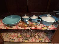 Photo showing six-piece set: three lidded ceramic bowls with handles, one large ceramic serving bowl, two wooden utensils, glass bowl set with dipping bowl and rack below.