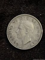 Obverse side of the 1948 One Shilling coin with profile of King George VI and inscriptions around edge.