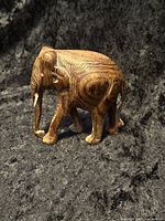 Front and side view of the hand carved wooden elephant figurine on a black textured background.