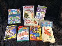 Full lot of kids card games arranged on black fabric, showing all games and box covers.