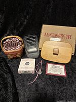 Longaberger mixed lot including wood lid, miniature basket with liner, plastic liner, tie-on and packaging.