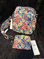 Lug Can Can convertible crossbody bag and matching Minuet wallet in a colorful wildflower pattern with tags visible, bag strap extended.