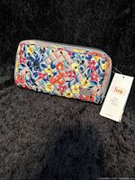 Front view showing quilted wildflower patterned wallet with silver Lug logo plaque and zippered closure.