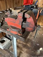 Front angle view of red Wilton USA bench vise mounted on a workbench, showing jaws, handle, and part of the base.