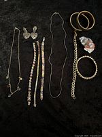 Full view of all assorted vintage jewelry laid out on dark fabric, showing variety of bracelets, necklaces, earrings, and bangles.