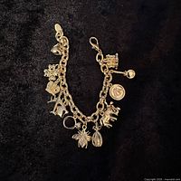 Full view of the Joan Rivers charm bracelet on black surface showing all charms