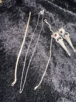 Vintage sterling silver jewelry lot featuring two necklaces, one bracelet, and ornate drop earrings with stones, with quarter for size reference.