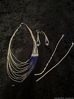 Full lot showing the multi-strand necklace with blue beads, matching earrings, and two silver bracelets.