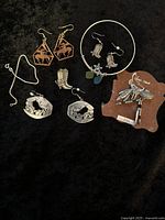 Full overview of jewelry lot displayed on black background, showing all items including earrings, bracelet, brooch, and necklace with quarter for size reference.