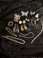 Overview of entire lot showing two bracelets, multiple earrings with various motifs, chains and brooches.
