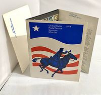 Fold-out souvenir folder with blue rider on horse illustration and red and white flag background, showing the front and partial interior with stamps.
