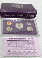 1990-S US Mint Proof Set plastic case with five coins and accompanying information sheet beneath it, placed in front of purple envelope with gold emblem and printed text.