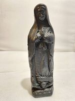 Front view of black clay Virgin Mary statue showing prayer pose and robe details.