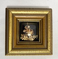 Full view of the gold framed shadow box containing the gold plated orchid and leaves against a black background