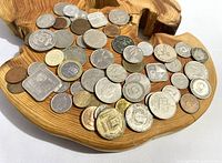 Top view of assorted international coins placed on a wooden surface showing coins of various shapes and materials.