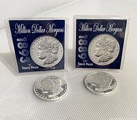 Pair of Morgan tribute proof coins with blue certificate sleeves, labeled 1889 'S' and 1893 'CC', coins positioned in front