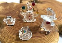 Four miniature glass figures: hippo, juggling clown, frog, and bird, displayed on a wooden surface. Hippo is largest, about 1.5 inches tall, figures show age-related wear.