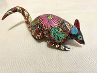 Side angle view of colorful hand painted armadillo figurine on white surface
