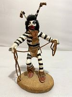 Front view of kachina doll showing painted stripes, fur hair and leather accents