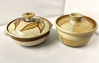 Photo showing both casseroles side by side with lids on, highlighting decorative leaf pattern and size difference.