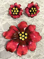 Red flower brooch and matching clip earrings on lace background, showing overall set and detail of flowers.