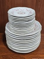 Stack of 23 plates, with larger dinner plates on bottom and smaller dessert plates on top, showing the profile and count of dishes.