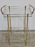Front view of the vintage Mid Century modern brass and glass table showing the brass bamboo style frame and two glass shelves. One glass shelf missing.