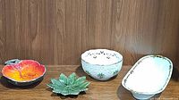 Group photo of four ceramic decorative dishes on wooden shelf: Lenox pierced round bowl, oval serving platter, orange/red leaf dish and green leaf dish.