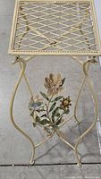Side angle view showing metal lattice top and legs with decorative metal flowers attached to the side frame.