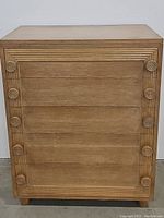 Front view of the oak dresser showing all 5 drawer fronts with circular carved wooden handles and detailed raised frames.