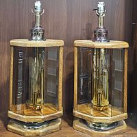 Pair of Don Ward etched amber glass panel lamps with wooden frames and brass bases shown from front on shelf.