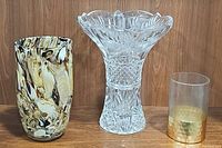 Three glass vases shown side by side on wooden surface with brown wood background