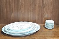 Stack of 3 oval serving platters and stack of 9 small round dishes with pink rose pattern