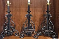 Front view of all three iron table lamps showing scrollwork design and black finish