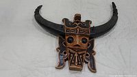 Front view of the carved wooden African tribal buffalo mask showing large eyes and detailed horns