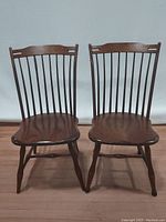 Two Amish spindle bow back Windsor wooden chairs, showing front view, rich brown color and spindle backs