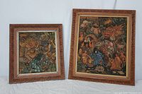 Two framed Balinese mythological paintings showing colorful mythical creatures and humans, both with detailed carved wood frames.