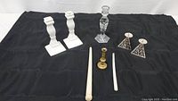 Full set of candleholders and candles on black cloth background showing arrangement and details of each item