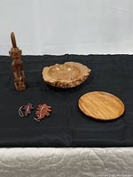 Full lot overview showing all carved items including statue, bowl, plate, and leaves arranged on a black cloth.