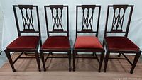 Set of four mahogany Chippendale style side accent chairs shown front view with red crushed velvet seats, one seat is a different red shade.