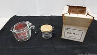 Photo showing a large Pyrex measuring cup, a small transparent plastic canister jar with a wooden lid and metal clasp, and an Aron Arom replacement glass carafe in original box.