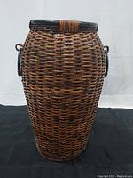 Front view of large woven rattan basket with wrapped wooden rim and circular handles.