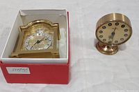 Two gold-toned Swiza clocks, the Tempus Frigile in red box on the left and the Sheffield alarm clock on the right.