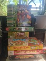 Photo of stacked game boxes including Jenga Xtreme, Jenga Quake, Fart, Funny Farm, Operation (Simpsons edition), Dizzy Dizzy Dinosaur, Battleship.