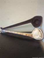 Full length view of the pipe alongside its original case. Pipe long and slender with a carved bowl.