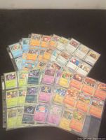 Photo showing multiple Pokémon cards in three rows arranged outside the page holder, including different Pokémon types and trainers.
